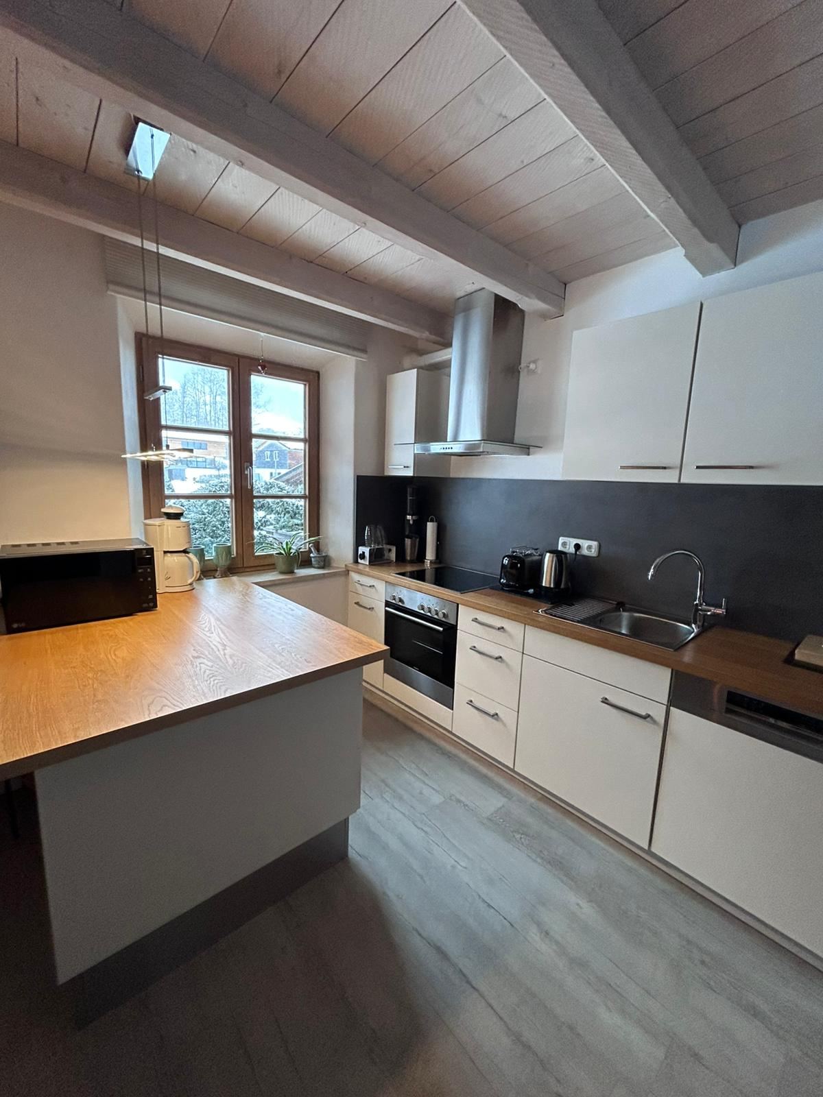 Küche der Ferienwohnung Bergblick mit Kochinsel, Backofen, Spüle und Dachschräge