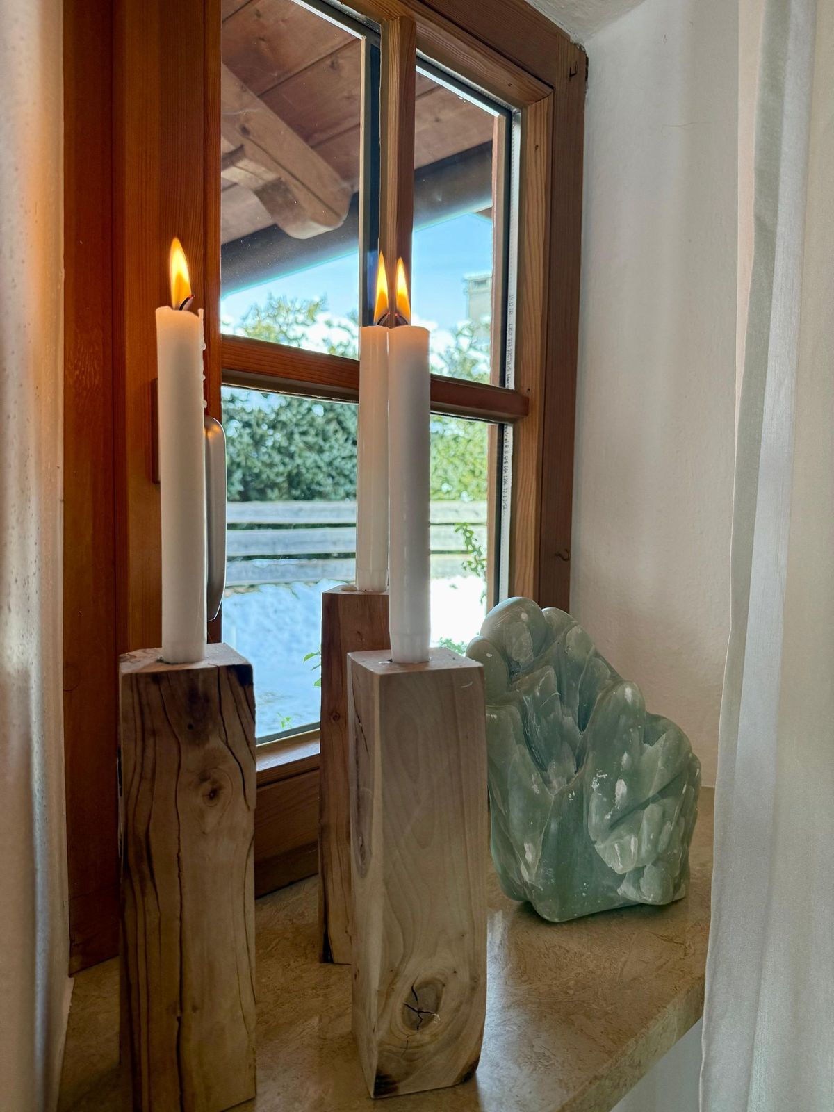 Kerzen auf Holzleuchtern am Fenster einer der Ferienwohnungen