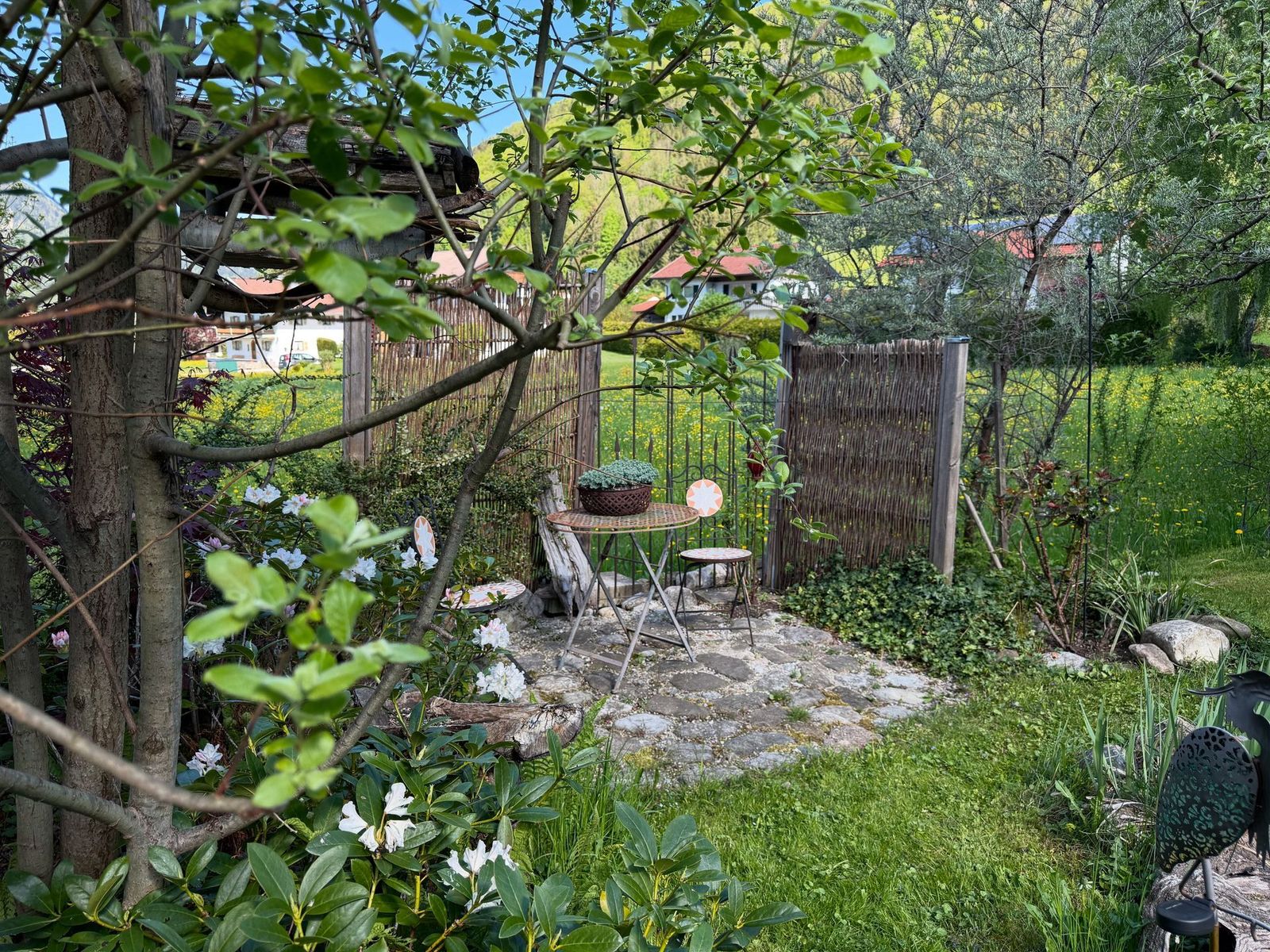 Freisitz im Garten mit Tisch und Stühlen zwischen blühenden Obstbäumen