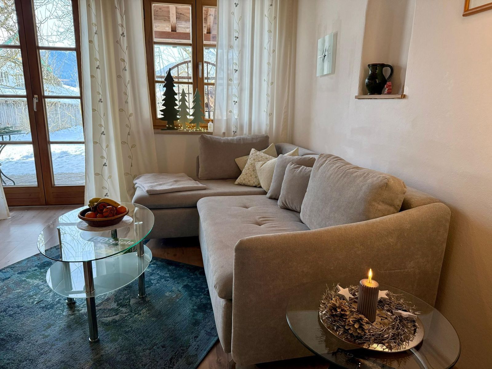 Wohnbereich der Ferienwohnung Sonnengarten mit Ecksofa, Glastisch und Holzbalkendecke